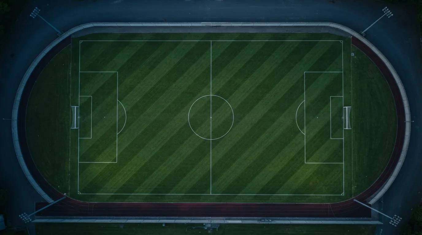 Ein Fußballplatz am Abend aus der Vogelperspektive, Flutlichtmasten ausgeschaltet, die Rasenlinien deutlich sichtbar.