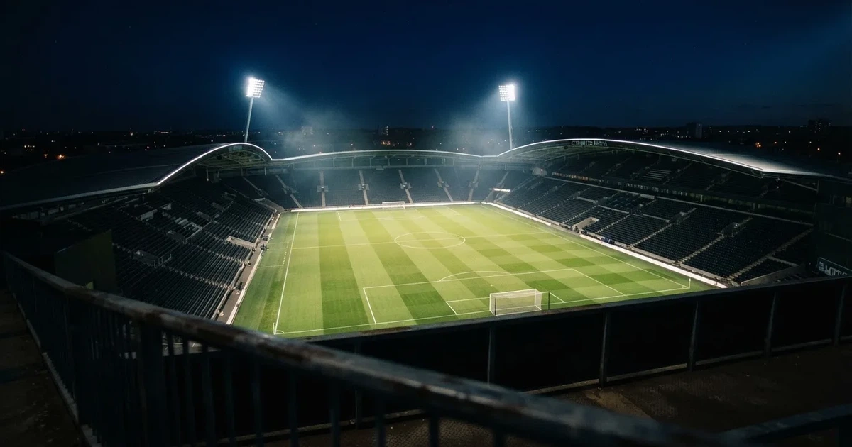 Ein Stadion bei Nacht unter Flutlicht aus der Ferne gesehen, der Rasen ist hell erleuchtet, keine erkennbaren Personen.